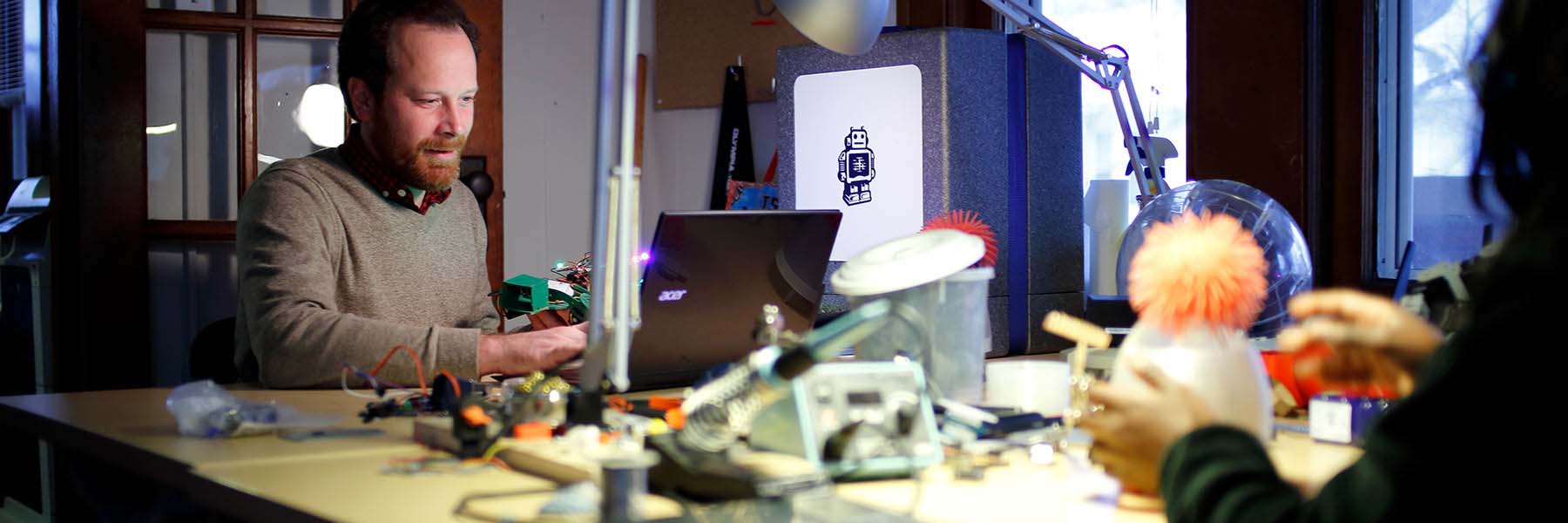 Researchers work at a table with robotics hardware.